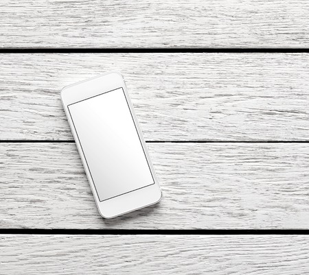 White smart phone on white wooden desk. Clipping path included.の写真素材