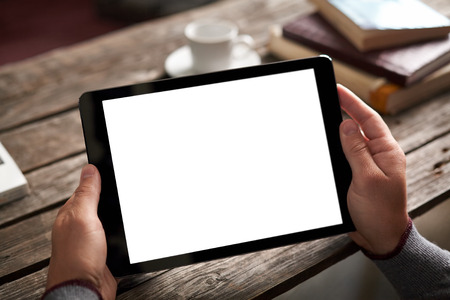 Digital tablet computer with isolated screen in male hands over cafe background - table, cup of coffee...