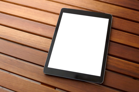 Digital tablet computer with isolated screen on wooden desk.