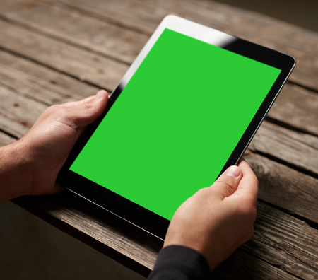 Digital tablet computer with isolated screen in male hands over cafe backgroundの写真素材