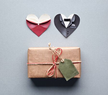 Vintage gift box with blank gift tag and symbolic male and female heart shapes on gray paper background.の写真素材
