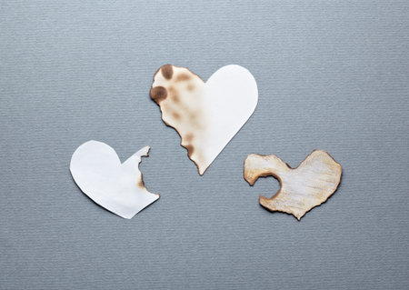 Different paper hearts. Partially damaged. Closeup on gray textured paper.の写真素材