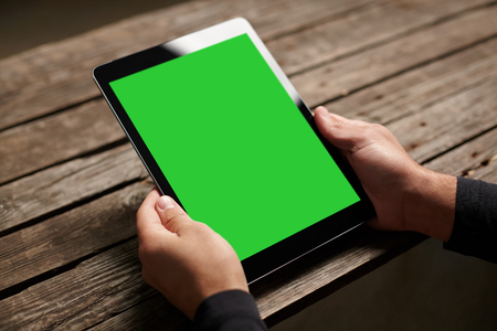 Digital tablet computer with isolated screen in male hands over cafe backgroundの写真素材