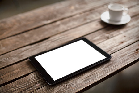 Digital tablet computer with isolated screen on wooden table with cup of coffeeの写真素材