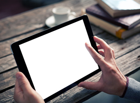 Digital tablet computer with isolated screen in male hands over cafe background - table, cup of coffee...の写真素材