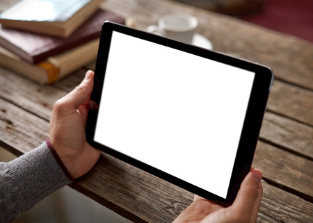 Digital tablet computer with isolated screen in male hands over cafe background - table, cup of coffee...の写真素材