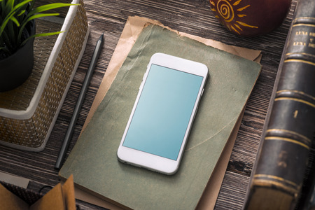 Template of white smartphone on the table with notes and old books. Clipping pathの写真素材