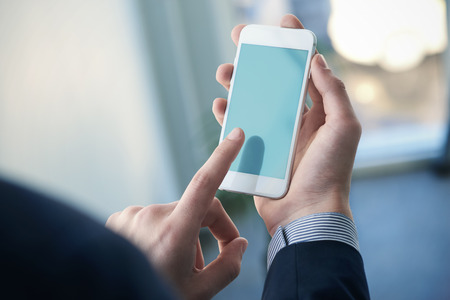 Mock up of a man holding device and touching screen. Clipping pathの写真素材