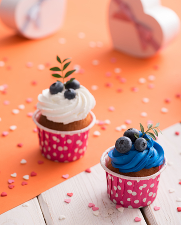 Tasty cupcakes with heart shaped gift boxes on a tableの写真素材