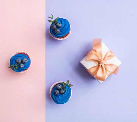 Cupcakes and gift box over two color plain background. Top view.の写真素材