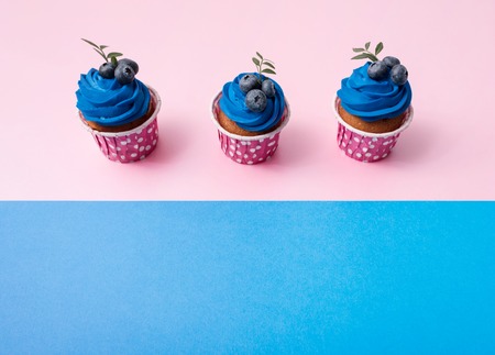 Three cupcakes in a row over two color plain background.の写真素材