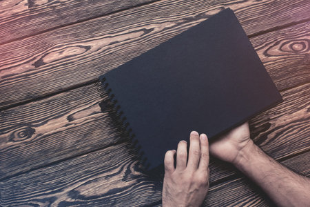 Man is going to open blank black brochure.