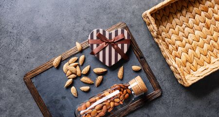 Heart shaped gift box with wild almonds around and empty wicker basket. Top view.の写真素材