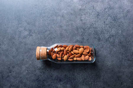 Almond nuts in corked glass jar on a concrete desktop
