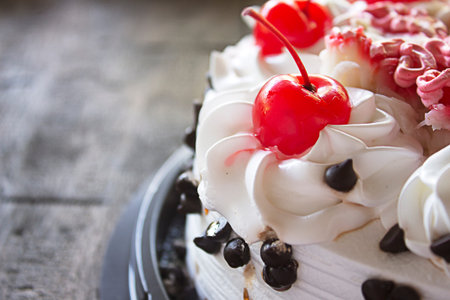 white cake with cherry topping on wooden tableの写真素材