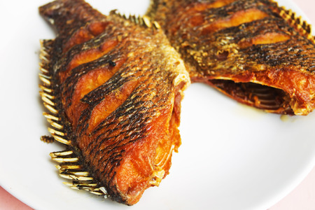 Fried red tilapia fish on white dishの写真素材