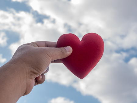 red heart on hand up blue sky cloud backgroundの写真素材
