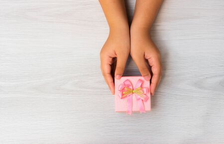 woman hands holding pink gift box on wood top viewの写真素材