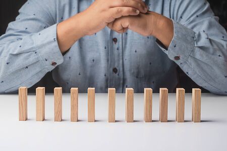 Businessman playing domino on desk.Risk management and insurance concept and Chain Reaction Domino Effectの写真素材