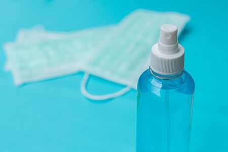 Surgical mask and spray alcohol for hand hygiene on green background.for the prevention of the flu and the Coronavirus, covid-19. Health care concept.Top viewの写真素材
