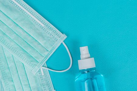 Surgical mask and spray alcohol for hand hygiene on green background.for the prevention of the flu and the Coronavirus, covid-19. Health care concept.Top viewの写真素材