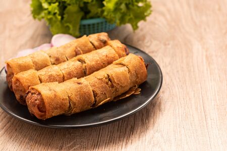 fried spring rolls and vegetables on black plateの写真素材