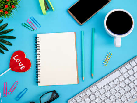 Top view workspace office business desktop blank Notepad with office accessories cup coffee on blue backgroundの写真素材