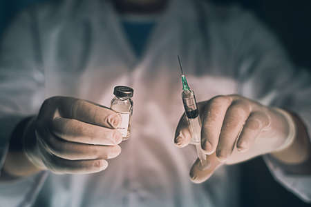Doctor filling syringe from vial and hands with medication, closeup. Vaccination and immunization injection.selective focus,vintage colorの写真素材