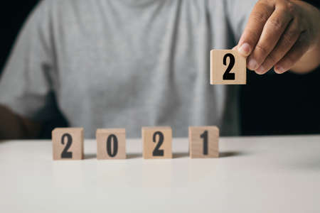 Businessman hand choose year 2022 on wood cube wooden cube block to change 2021 year to 2022 year , start new target conceptの写真素材