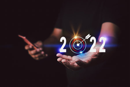 New year 2022 and goal or target icon. concept of New year Business goals and vision.Hand hold smartphone and target arrow 2022 icon copy space for textの写真素材