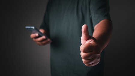 Businessman using mobile phone pointing up and showing with thumb up for touch