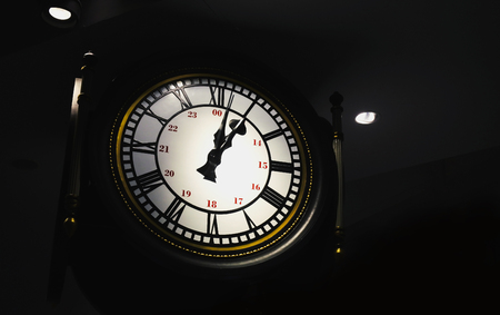A large clock in the dark with dim light. Watch the clock. Work takes timeの写真素材