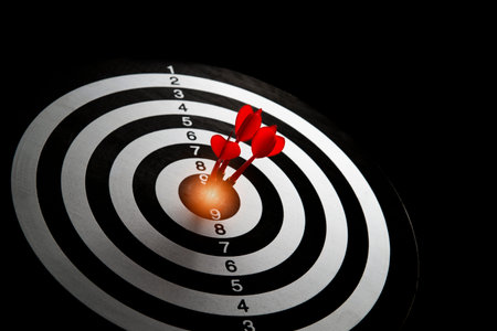 <p>A red dart in the middle of a target board with a black background. The concept of setting goals...