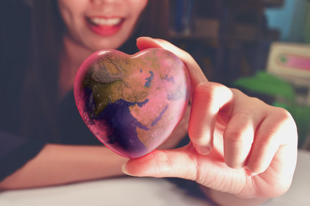 The girl has a heart-shaped world in her hand. World protectionism.の写真素材