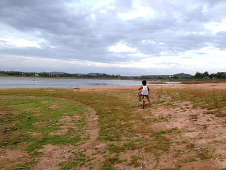Kid on a bike ride standing by a lakeの写真素材