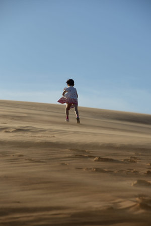 Young girl walking up a sand dune in the desert の写真素材
