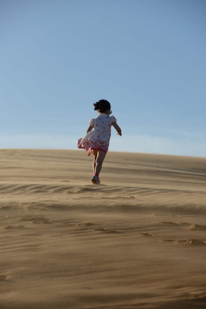 Young girl walking along a sand dune in the desert の写真素材