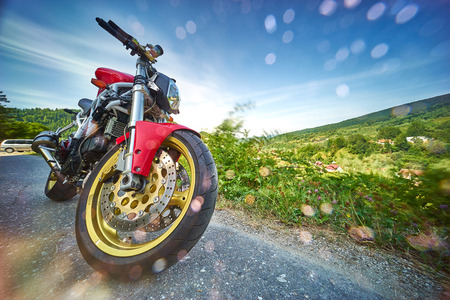 Red motorbike on rainy mountain road landscape.の写真素材