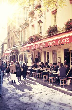 street in paris with cafe and parisians enjoying the sunny dayのeditorial素材