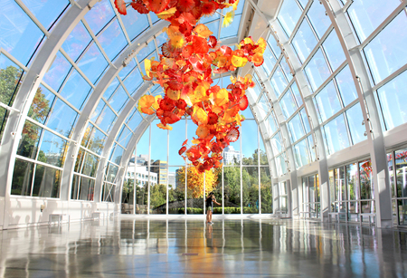 SEATTLE, July 29, 2017: Chihuly Garden and Glass museum featuring one of Dale Chihuly's largest sculptures suspended from the ceiling of the glasshouse. City buildings are seen in the background.のeditorial素材