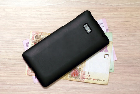 mobile phone and Ukrainian hryvnia on the table