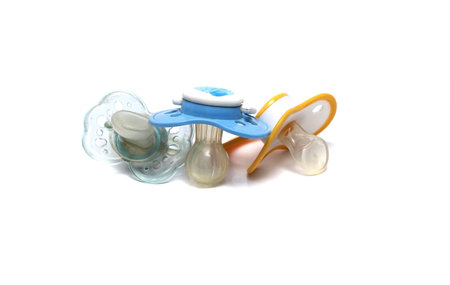 three dirty pacifiers on a white background