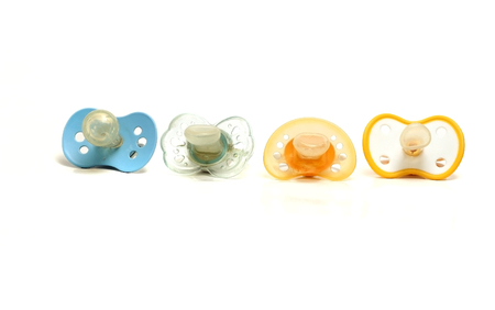 four dirty pacifiers on a white backgroundの写真素材