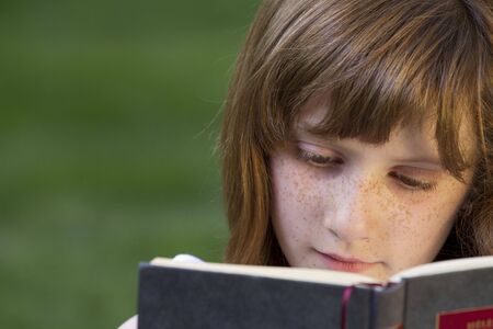 Young beautiful girl reading a book outdoorの写真素材
