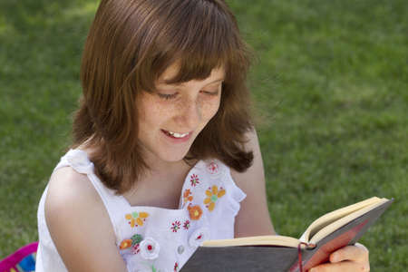 Young beautiful girl reading a book outdoorの写真素材