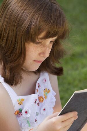 Young beautiful girl reading a book outdoorの写真素材