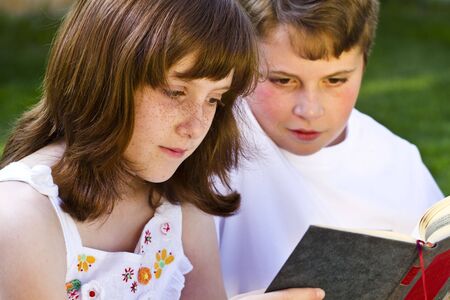 Portrait of cute kids reading books  in natural environmentの写真素材