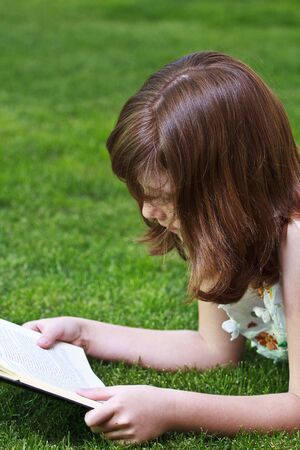 Young beautiful girl reading a book outdoorの写真素材