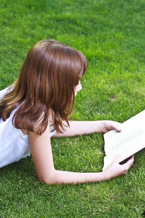 Young beautiful girl reading a book outdoorの写真素材