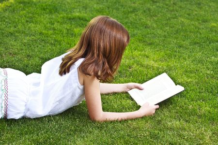 Young beautiful girl reading a book outdoorの写真素材